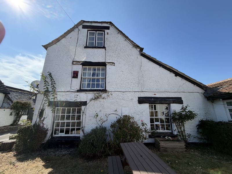 The gable end of the pub with picnic benches in the sunshine