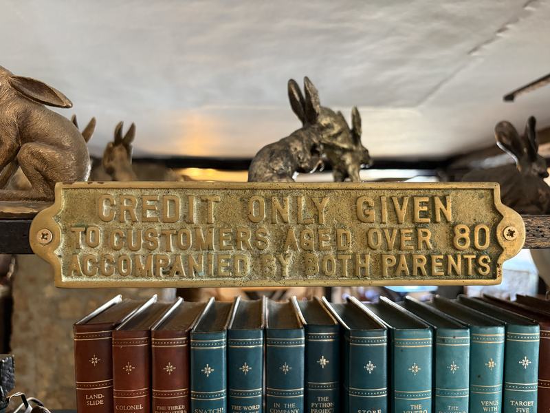 A brass sign reading Credit only given to customers aged over 80 accompanied by both parents