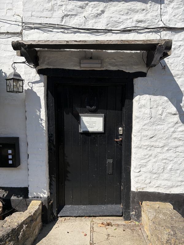 The black plank front door with an iron lantern beside it