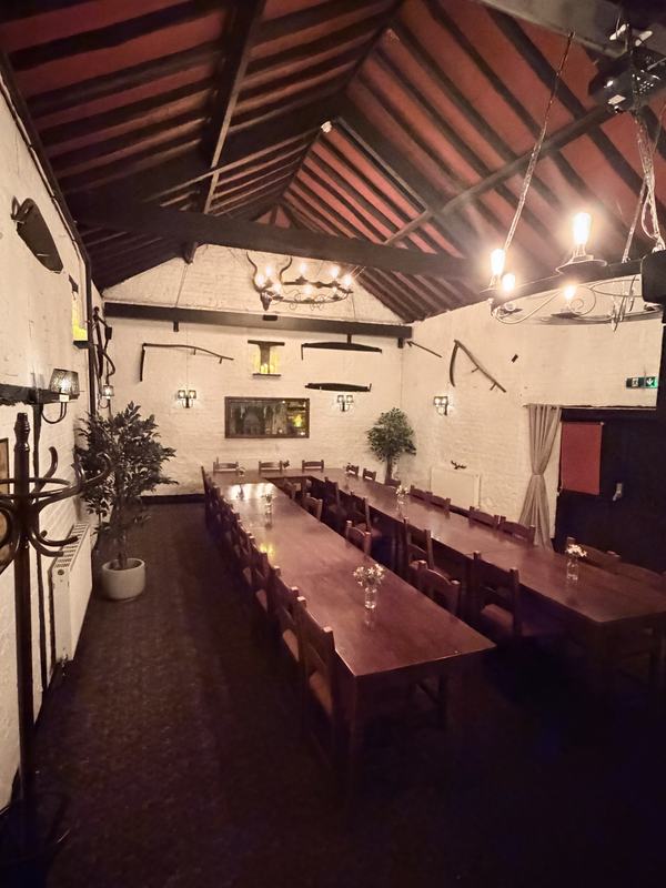 Iron chandeliers hanging from the open timber roof of the function room
