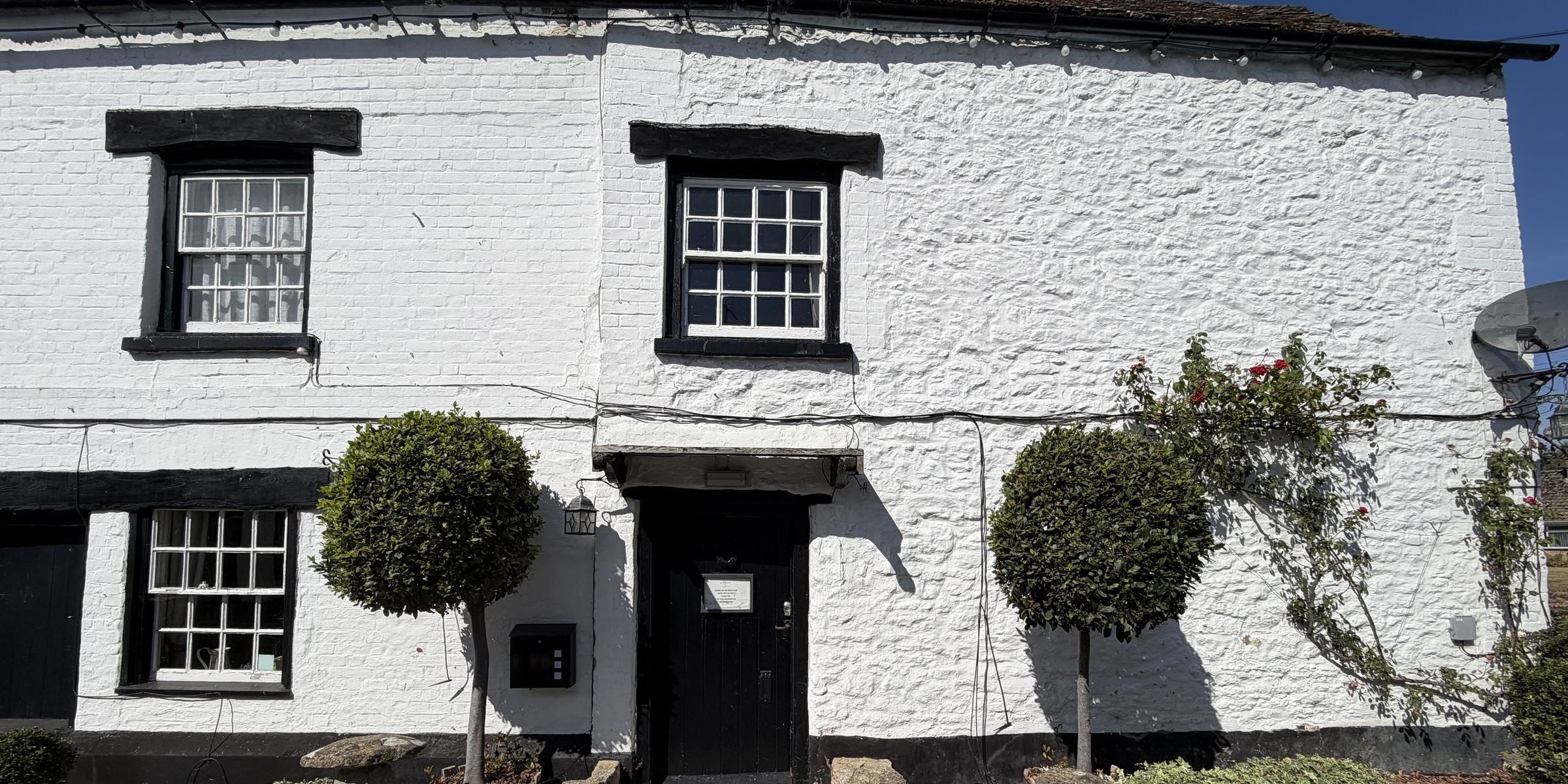The whitewashed front of The Woodman Inn, Fernham, with its black-framed sash windows