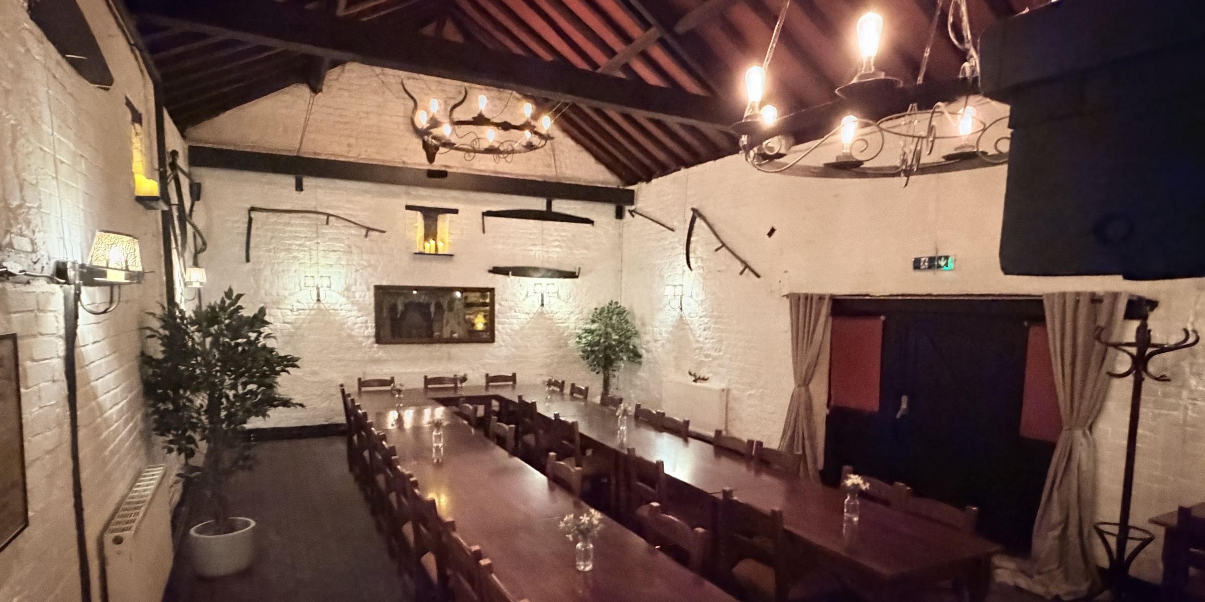 The Medieval Function Room laid for a party, with long banqueting tables beneath iron chandeliers and an open timber roof