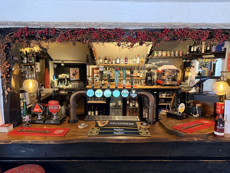 The bar at The Woodman Inn, with hand pumps, optics and the coffee machine behind
